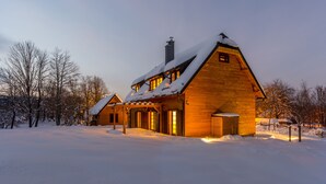 A wooden cabin with a steep roof, surrounded by snow-covered ground and trees. - Fenomen Plitvice (Plitvicka Jezera)
