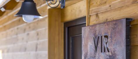 A rustic wooden wall with a metal sign reading "VR" and a black bell hanging from a metal fixture.