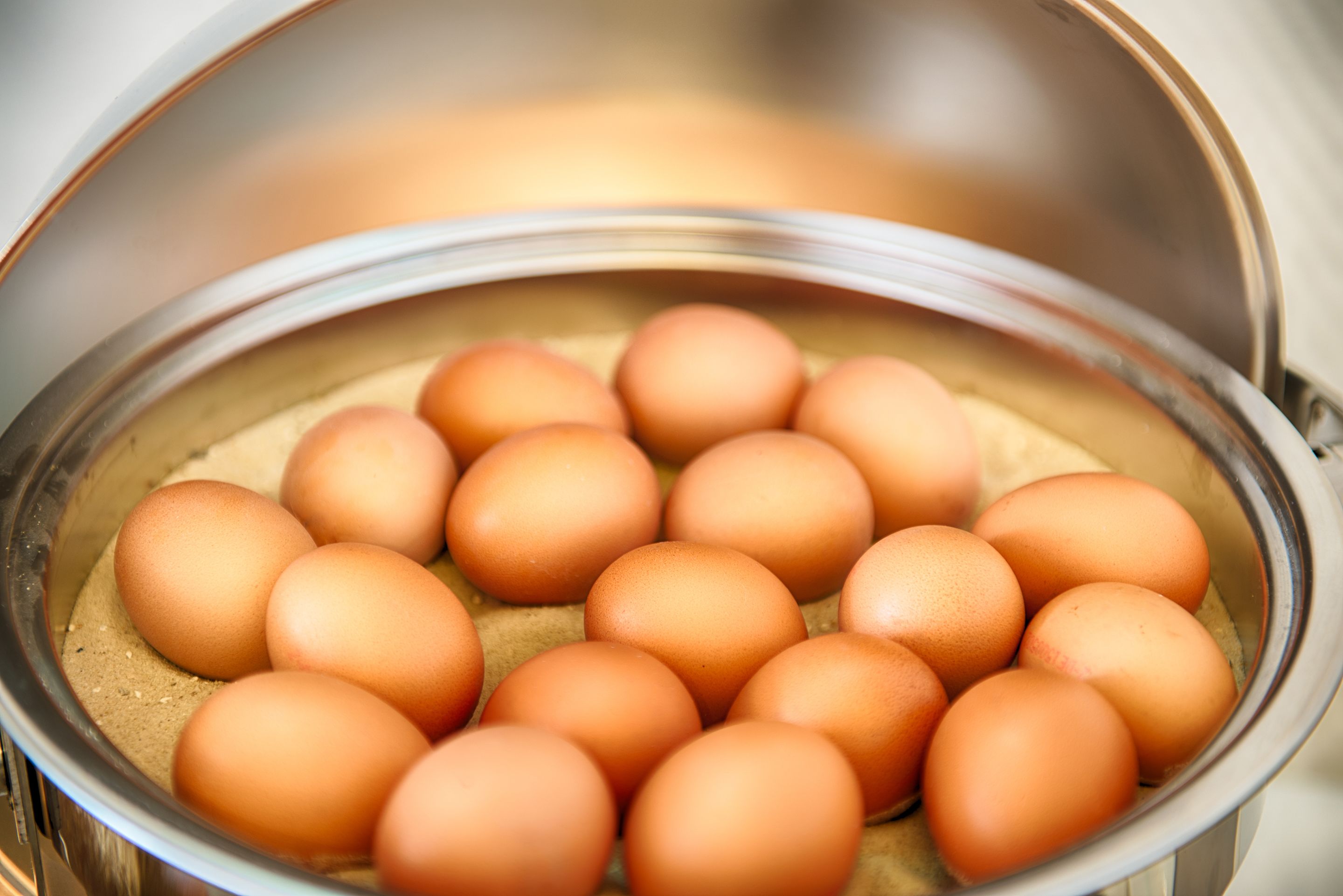 A stainless steel pot containing multiple eggs.