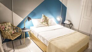A neatly arranged bedroom with a bed, a chair, a desk, and a lamp.