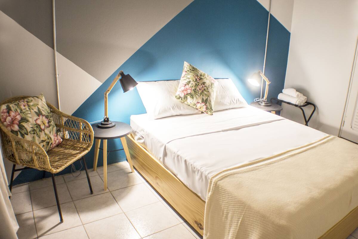 Een keurig opgemaakt slaapkamer met een bed, een stoel, een bureau en een lamp.