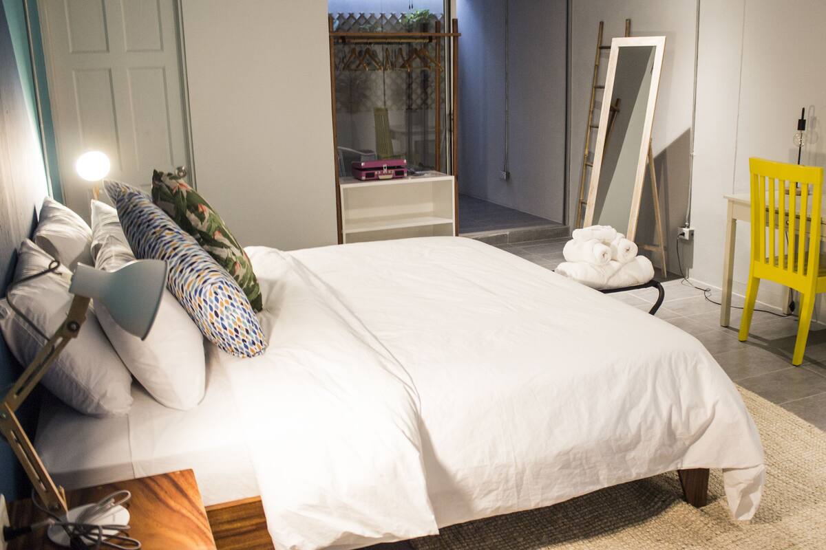Een keurig opgemaakt slaapkamer met een bed, bureau, stoel en spiegel.