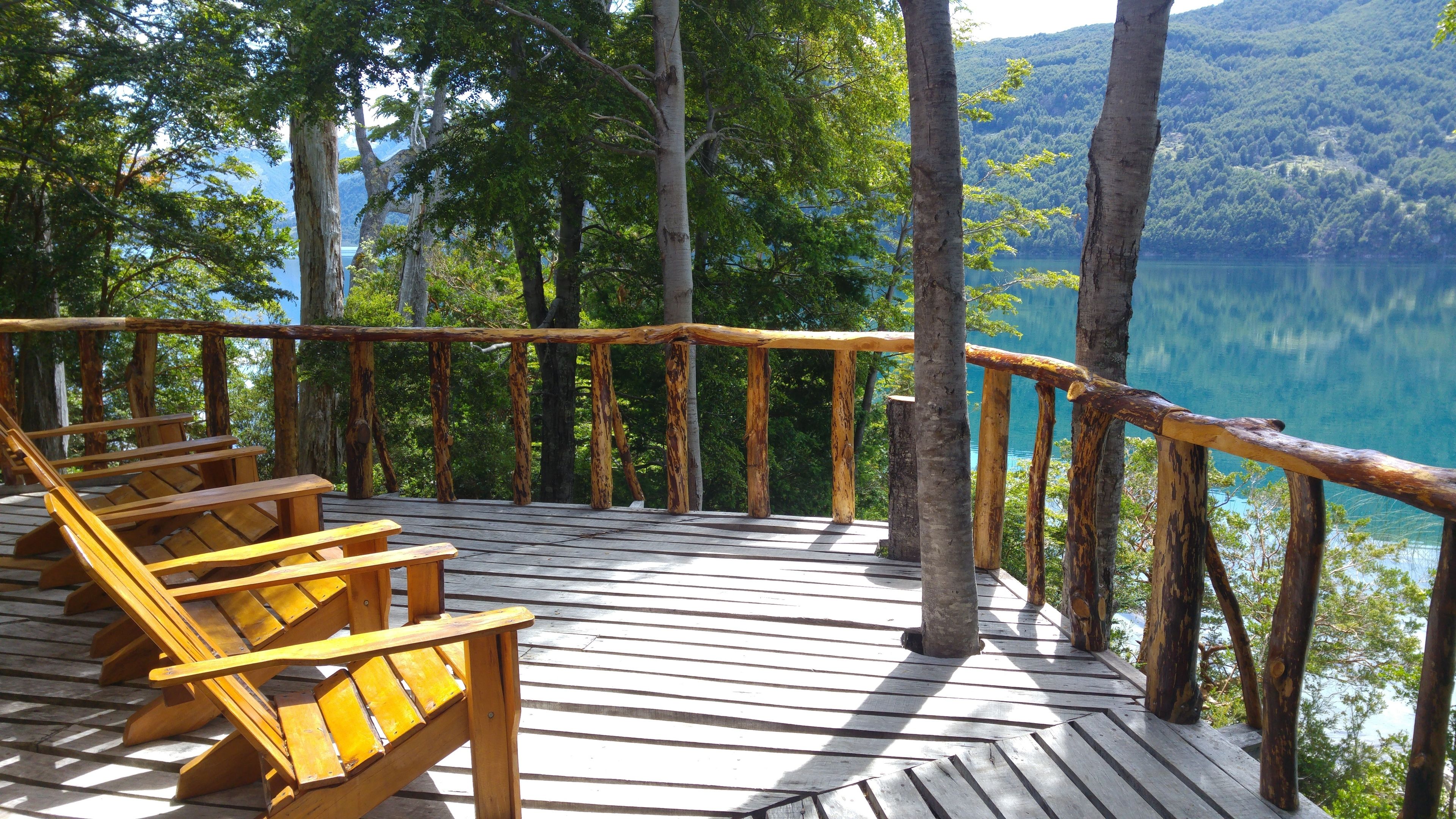 A wooden deck with benches overlooking a lake and forested hills.