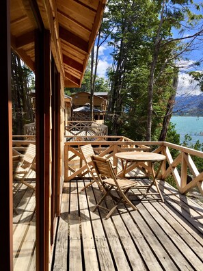A wooden deck with outdoor seating and a view of a lake and mountains. - Alma Patagonia Lodge (Futaleufú)