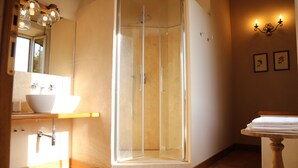 Ein Badezimmer mit einer Duschkabine, einem weißen Waschbecken und einer Holzanrichte.