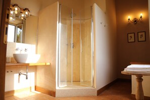 A bathroom with a glass-enclosed shower, a white sink, and a wooden vanity.
