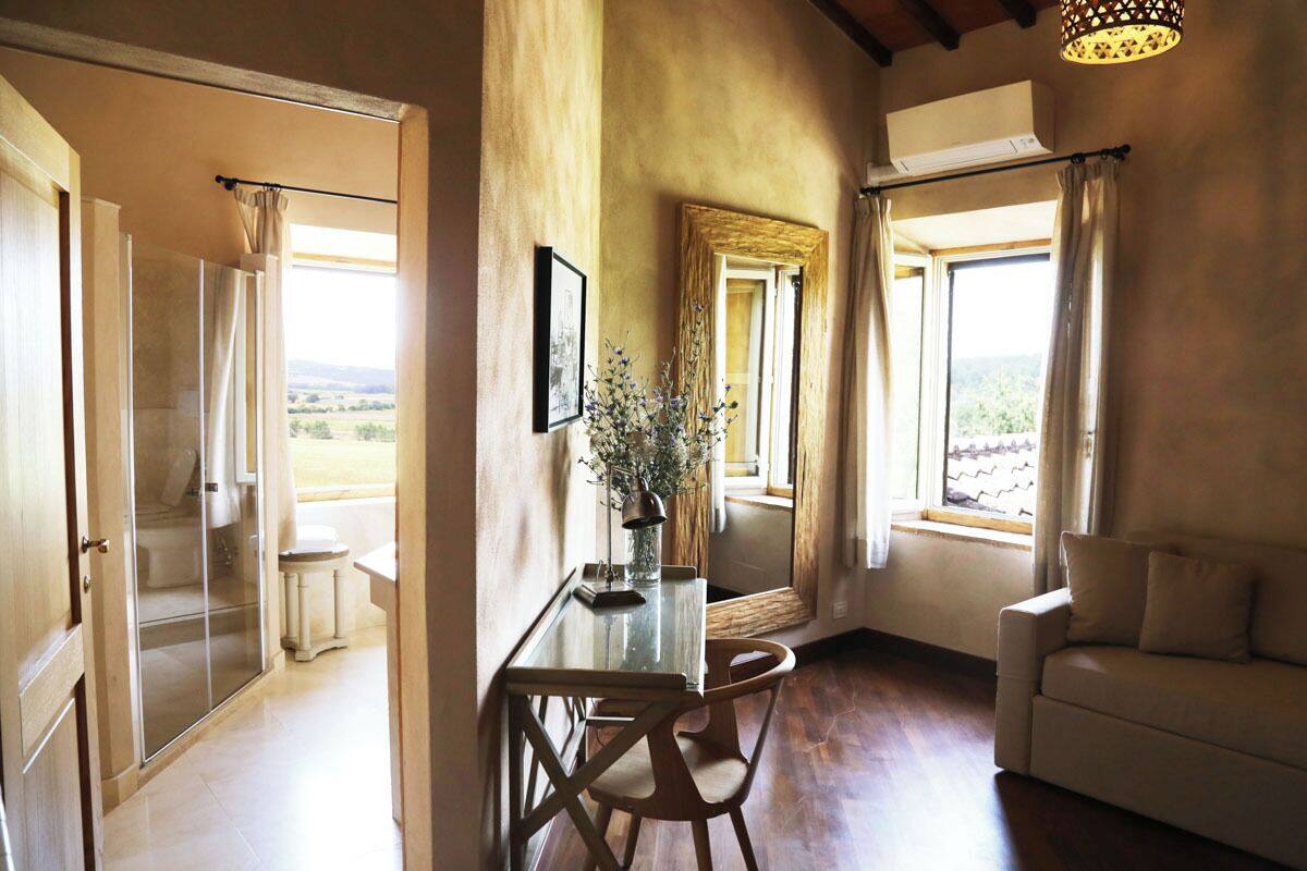 Een kamer met een glazen tafel, een bank en uitzicht op het landschap.