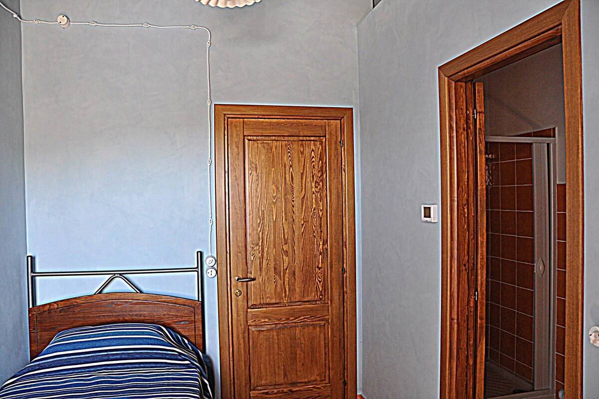 A bedroom with a bed, a wooden door, and a bathroom visible through an open door.