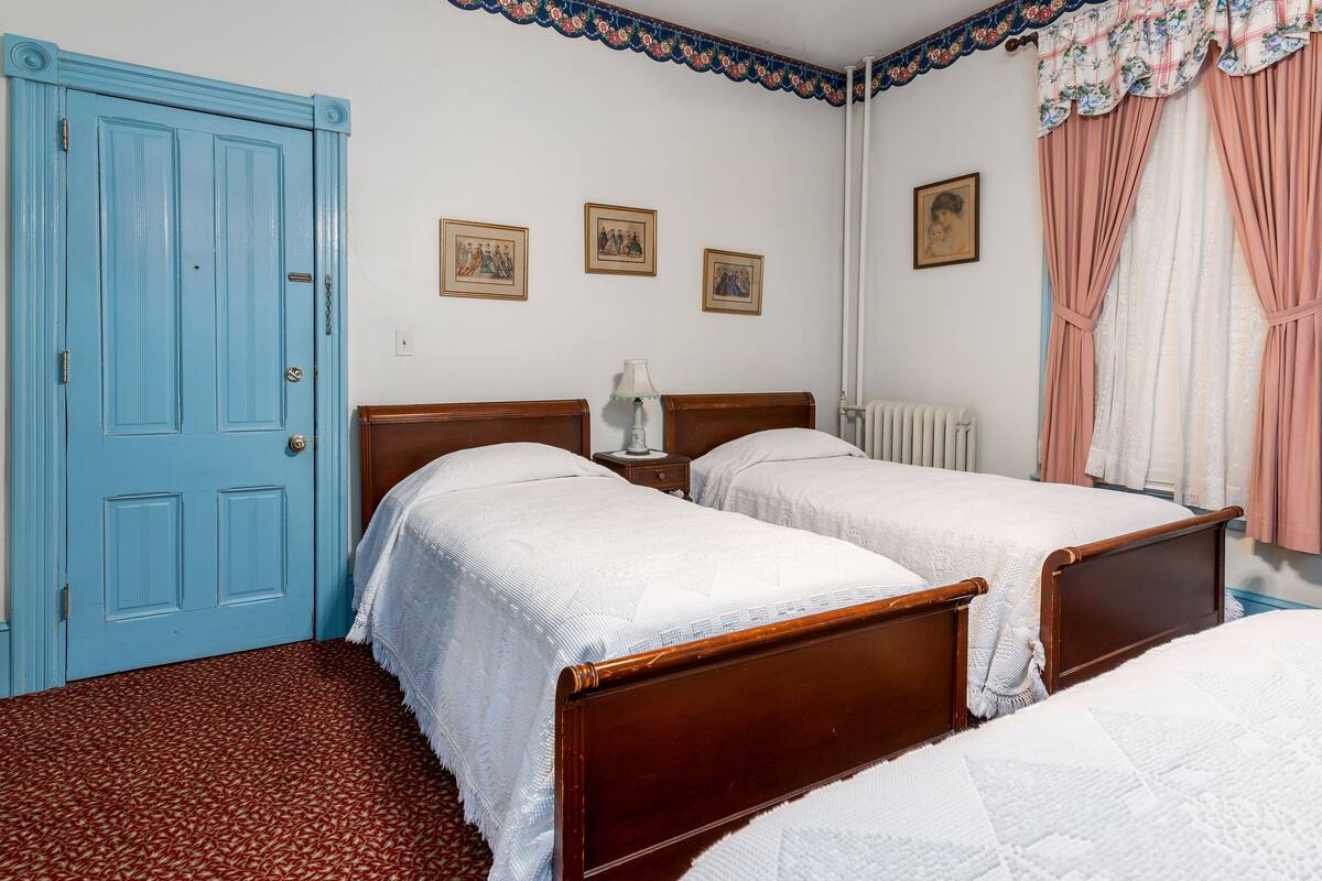 A room with two wooden beds, a blue door, and a radiator.
