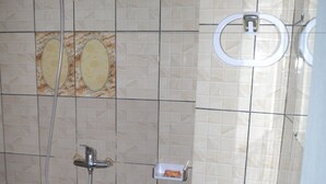 A bathroom with a sink, a shower with a handheld showerhead, and a toilet. - Hôtel Ma Résidence (Abidjan)