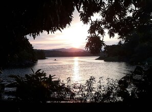 Un atardecer sobre un río tranquilo rodeado de vegetación.