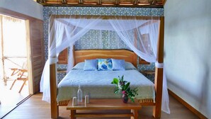 Una cama con dosel, cabecera de madera y mesita de noche con un jarrón de flores.