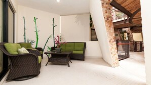 A modern living room with wicker furniture, a green sofa, and a coffee table. - Heliko 101A by CocoBR (Playa del Carmen)