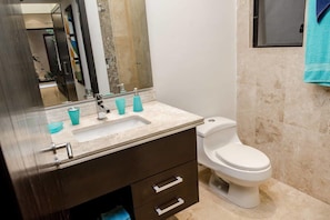 Een moderne badkamer met een marmeren wastafel, toilet en een grote spiegel.