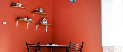 Un comedor con pared roja, techo de madera y una mesa con sillas.