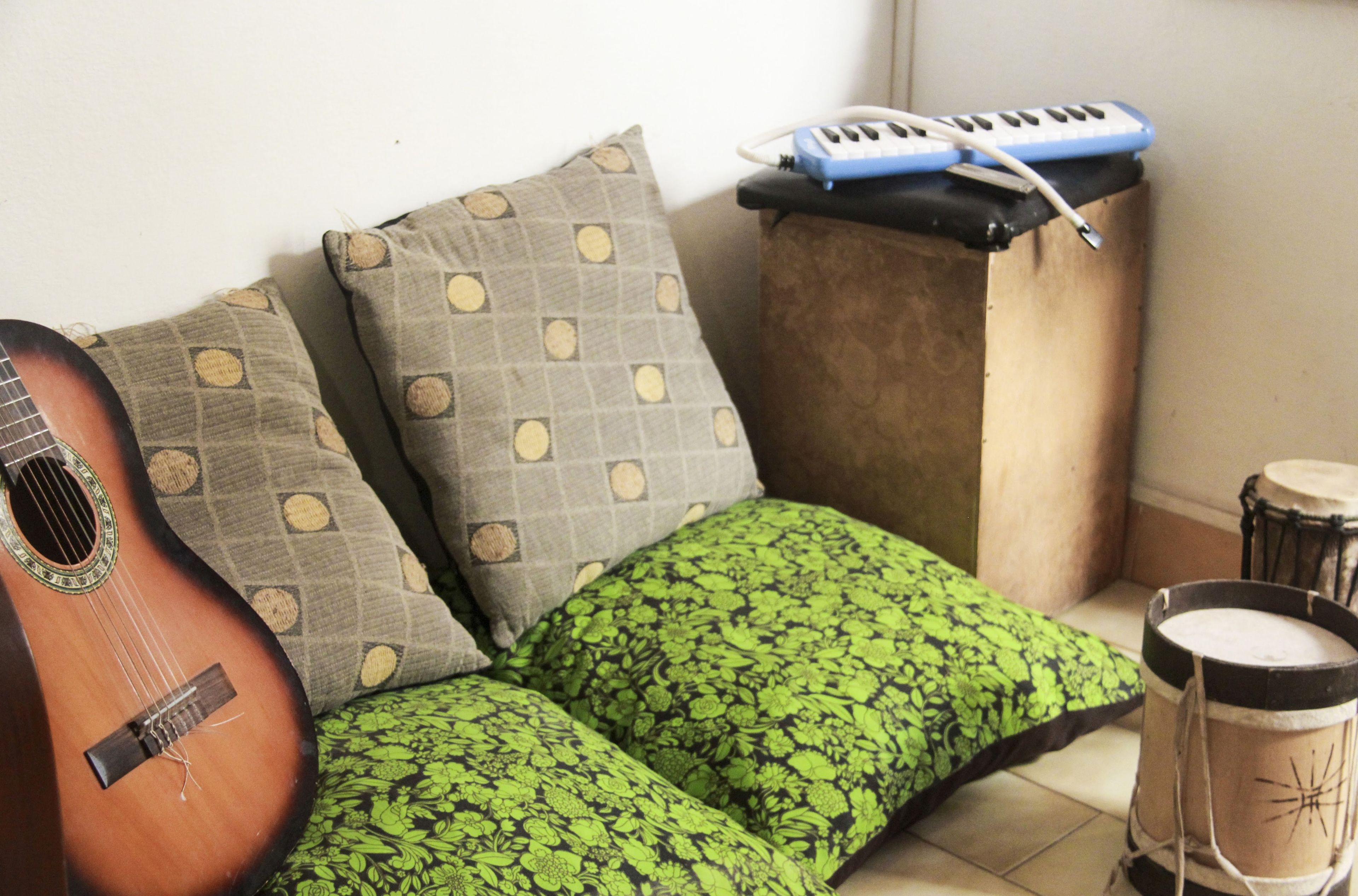 A corner of a room with a guitar, a keyboard, and a drum set.
