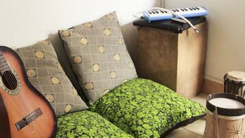 A corner of a room with a guitar, a keyboard, and a drum set.