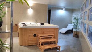 Ein Badezimmer mit einer Holzbadewanne, einer Duschkabine und einer kleinen Holzbank.