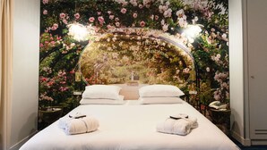 A hotel room with a large bed, two bedside tables, and a floral wall mural. - Hôtel Mercure Paris Suresnes Longchamp (Suresnes)