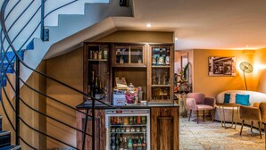 A hotel lobby with a staircase, a minibar, a seating area with a sofa and chairs, and a wall-mounted picture. - Hôtel Mercure Paris Suresnes Longchamp (Suresnes)