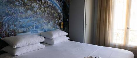 A hotel room with a bed, pillows, a robe, and a floral wall mural.