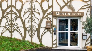 The exterior of the Mercure Hotel with a tree-like facade design and a sign indicating its location in Paris, Suresnes, Longchamp. - Hôtel Mercure Paris Suresnes Longchamp (Suresnes)