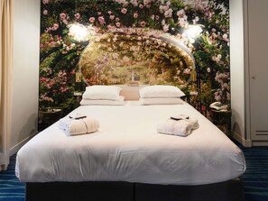 A hotel room with a large bed, two bedside tables, and a floral wall mural. - Hôtel Mercure Paris Suresnes Longchamp (Suresnes)