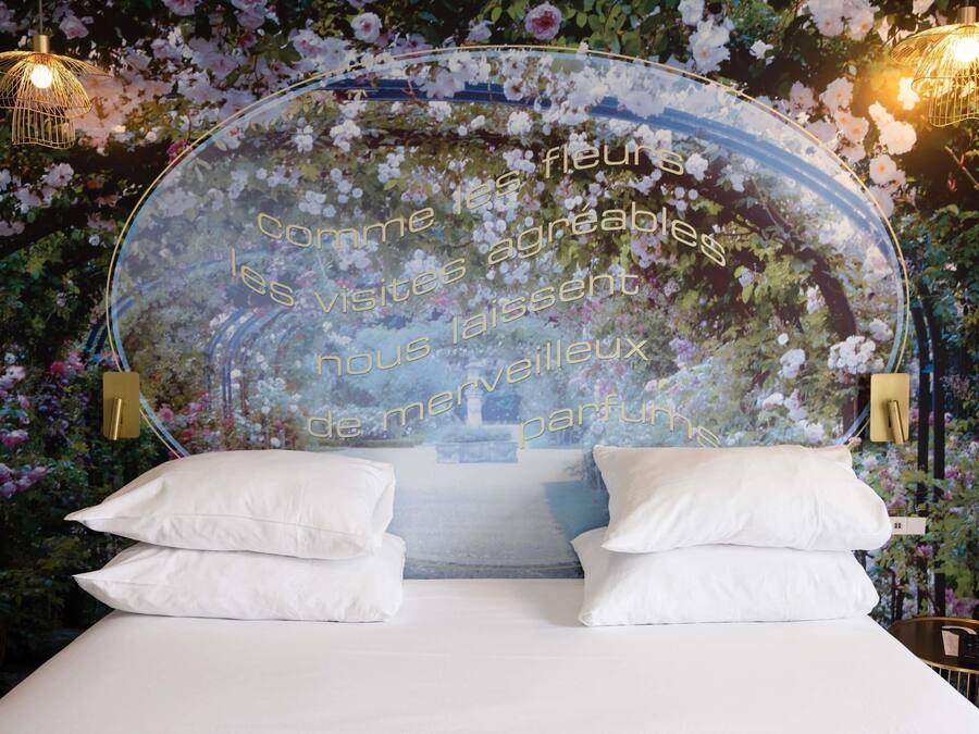 Una camera da letto con carta da parati a motivi floreali, un letto con biancheria bianca e due lampade a parete.