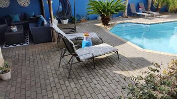 Una piscina al aire libre, sillones reclinables de piscina
