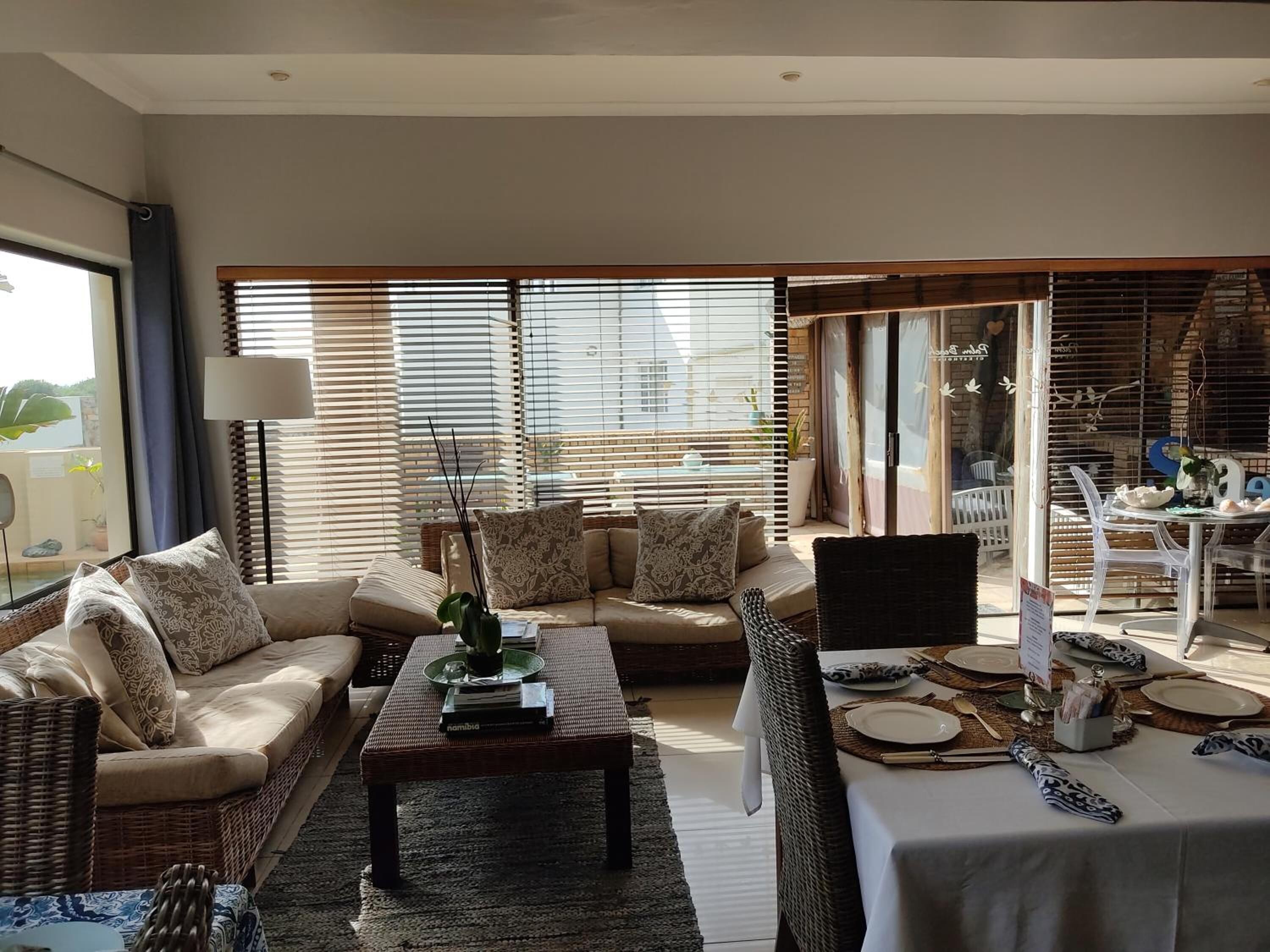 Una sala moderna con un conjunto de sofás, una mesa de centro y un comedor con una mesa dispuesta para dos personas.