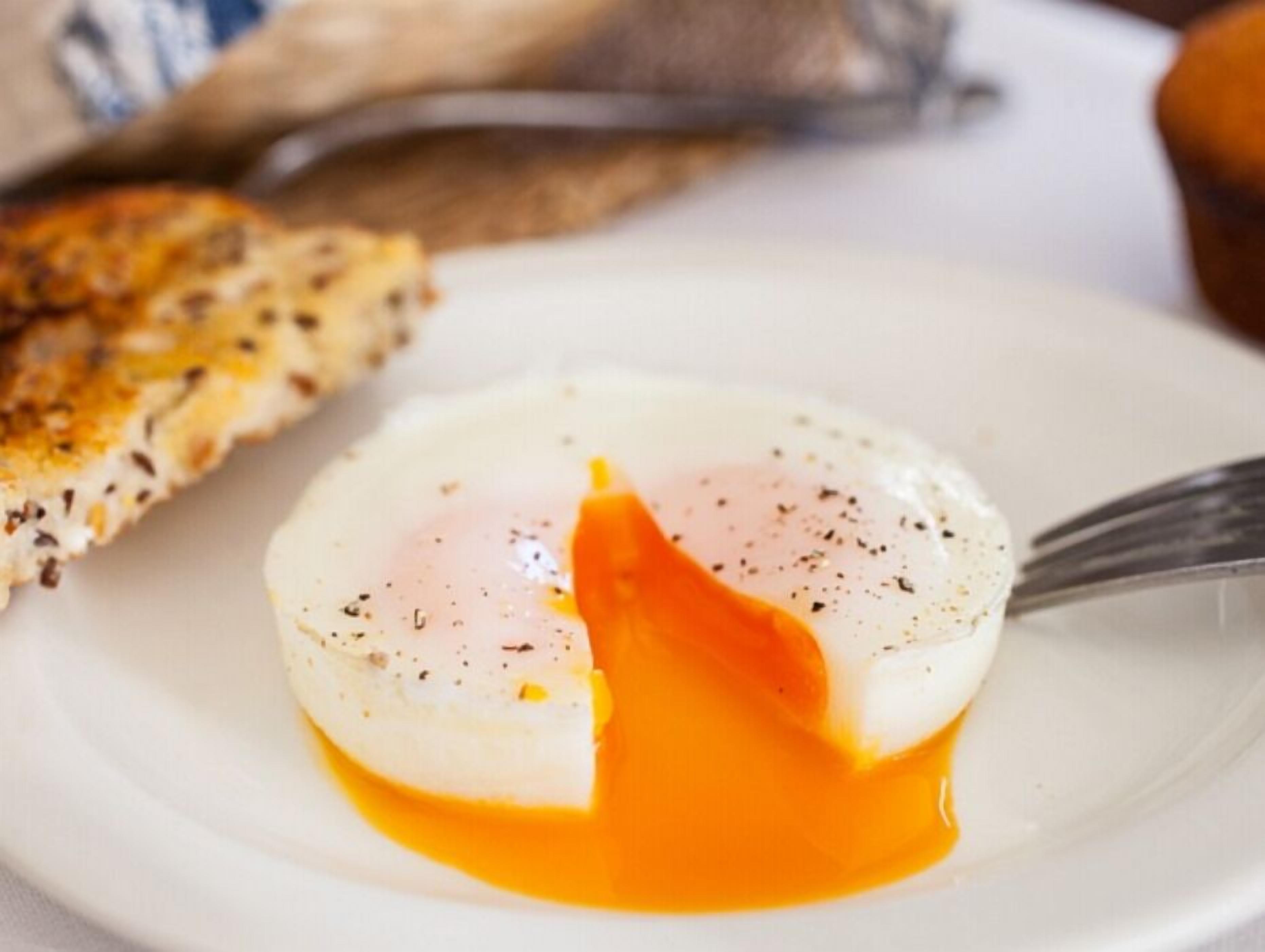 A poached egg on a white plate with a fork.