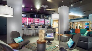Et moderne loungeområde med behagelige siddepladser, en bar med oplyste hylder og en trappe til et niveau ovenover.