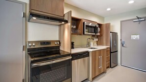 A modern kitchen with stainless steel appliances, wooden cabinets, and a built-in microwave. - Home2 Suites by Hilton Columbus Downtown (Columbus)