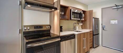 A modern kitchen with stainless steel appliances, wooden cabinets, and a built-in microwave.