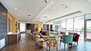 A modern hotel lobby with a sofa, chairs, a coffee table, and a kitchen area. - Home2 Suites by Hilton Columbus Downtown (Columbus)