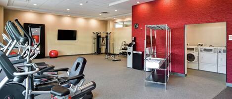 A gym with treadmills, weight machines, and a red wall.