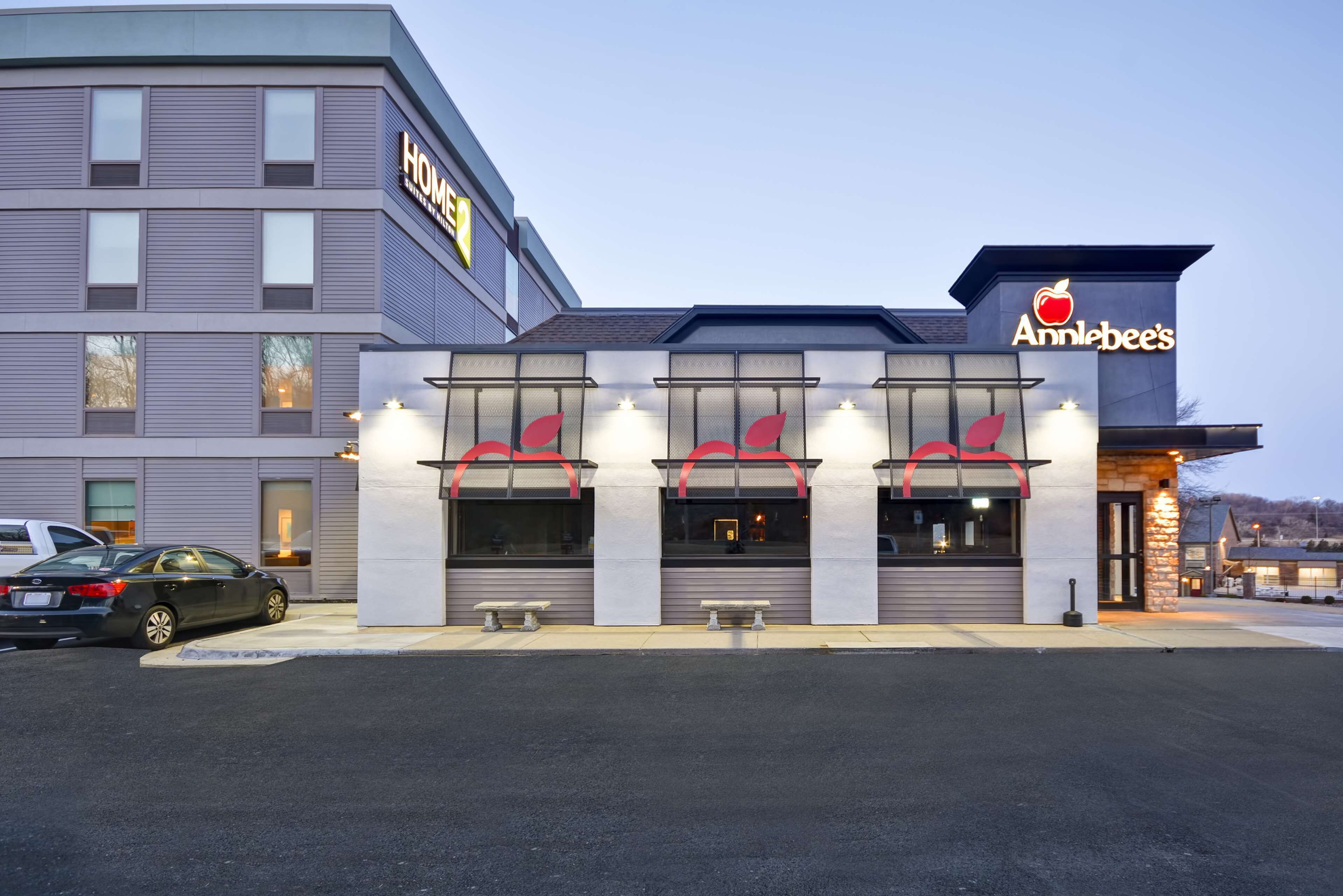 Et hotel med en moderne facade, et tydeligt skilt for restauranten "Anniebee's" og en parkeringsplads med biler.