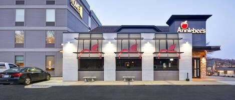 A hotel with a modern facade, a prominent sign for "Anniebee's" restaurant, and a parking lot with cars.