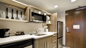 Una cocina moderna con microondas de acero inoxidable, lavavajillas integrado y refrigerador.