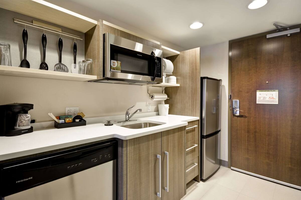 A modern kitchen with a dishwasher, a refrigerator, a microwave, and a coffee maker.
