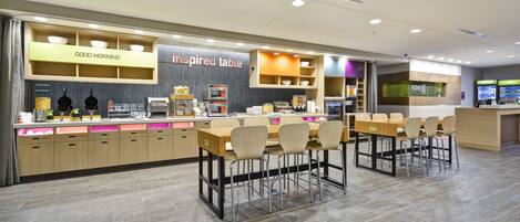 Un café moderne avec une enseigne « Bonjour », un espace « Table d’inspiration » et un comptoir « Home2 ».