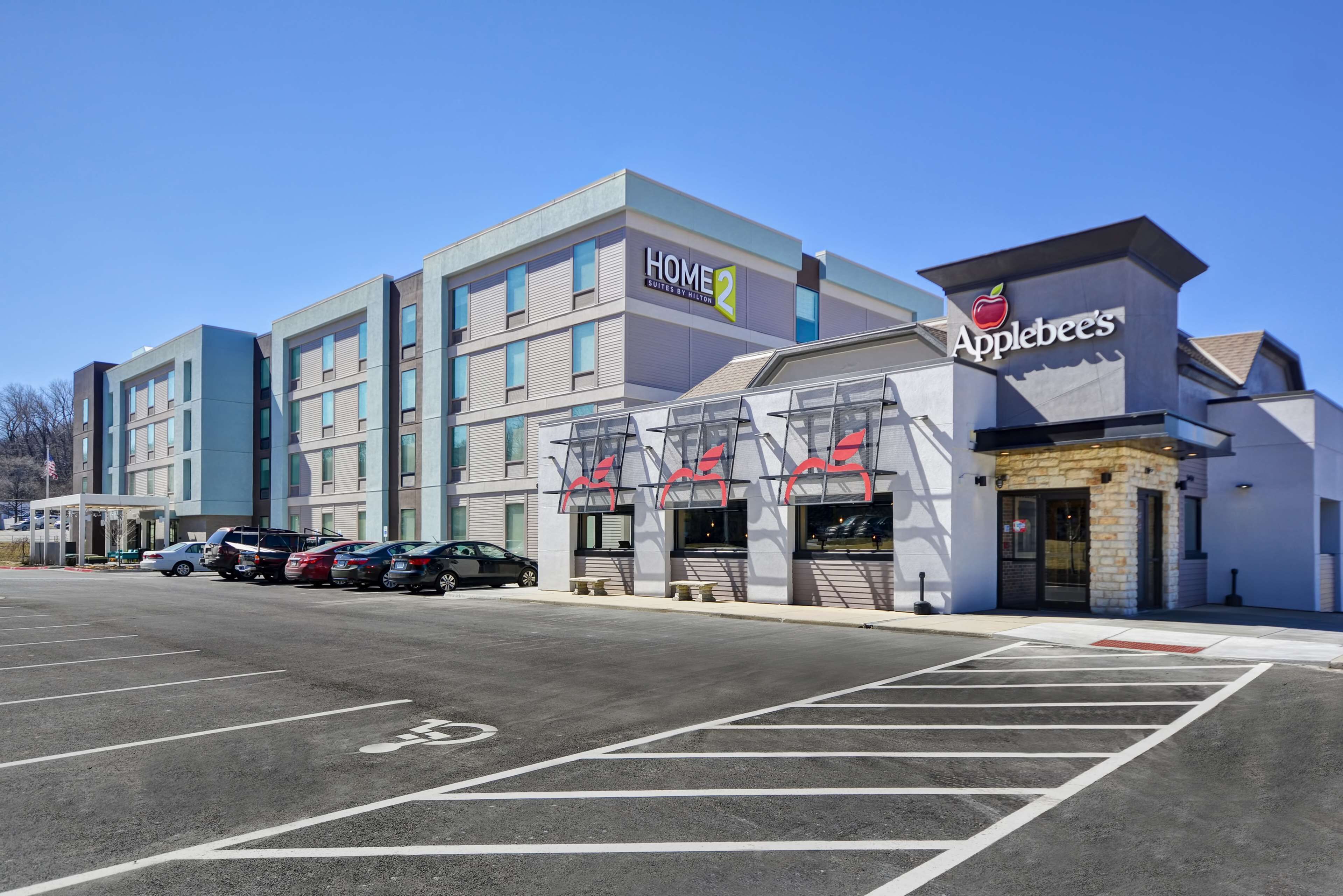 Um hotel de vários andares com design moderno, com um restaurante Applebee's bem visível no térreo.