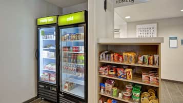 A vending machine area with two refrigerated units labeled "really cold" and "cold," and a shelf stocked with various food items and beverages.
