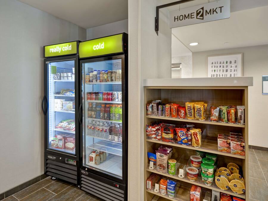 A vending machine area with two refrigerated units labeled "really cold" and "cold," and a shelf stocked with various food items and beverages.