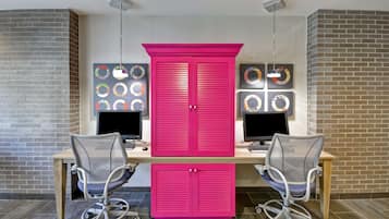 A workspace with two desks, two chairs, and a large pink cabinet.