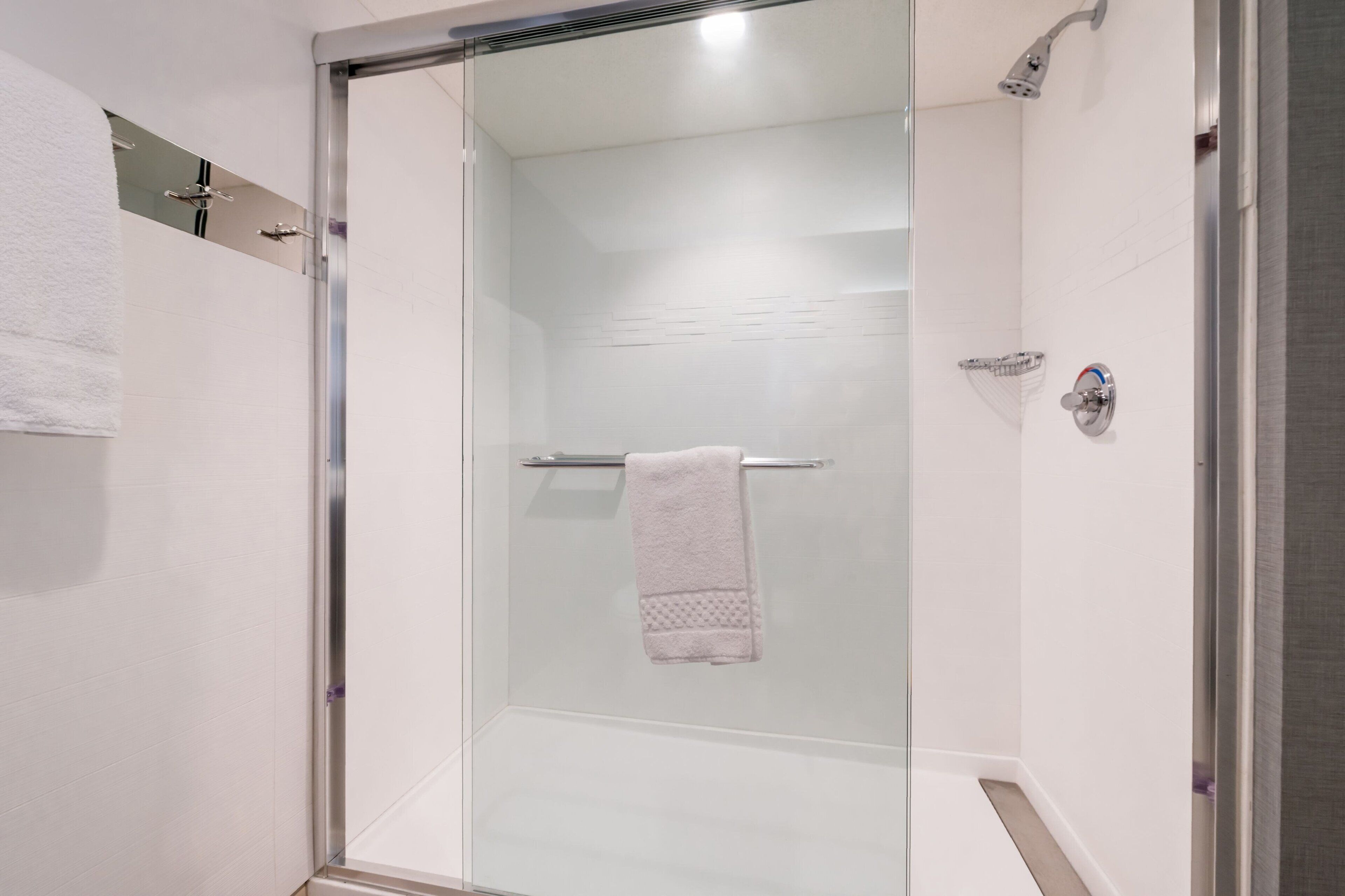 A modern bathroom with a glass shower enclosure, a towel rack, and a visible showerhead.