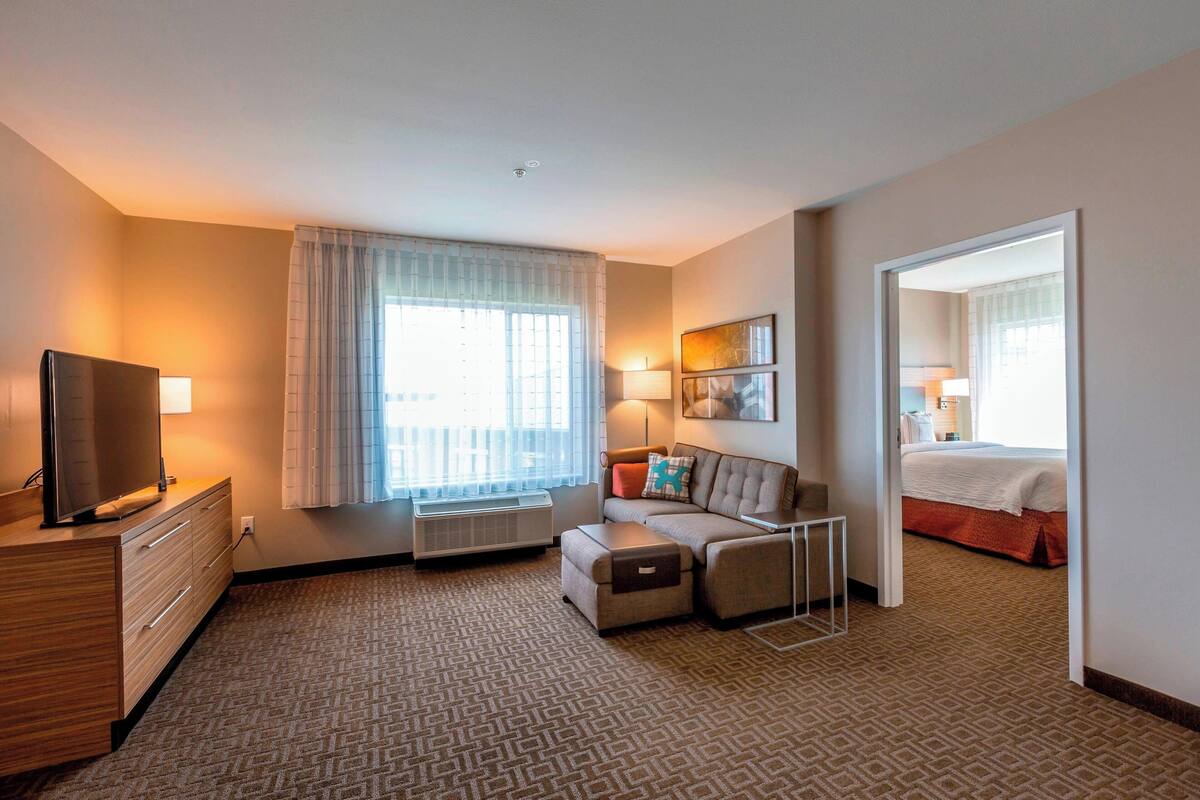 Ein Hotelzimmer mit einer Couch, einem Fernseher, einem Schreibtisch und einem Bett.