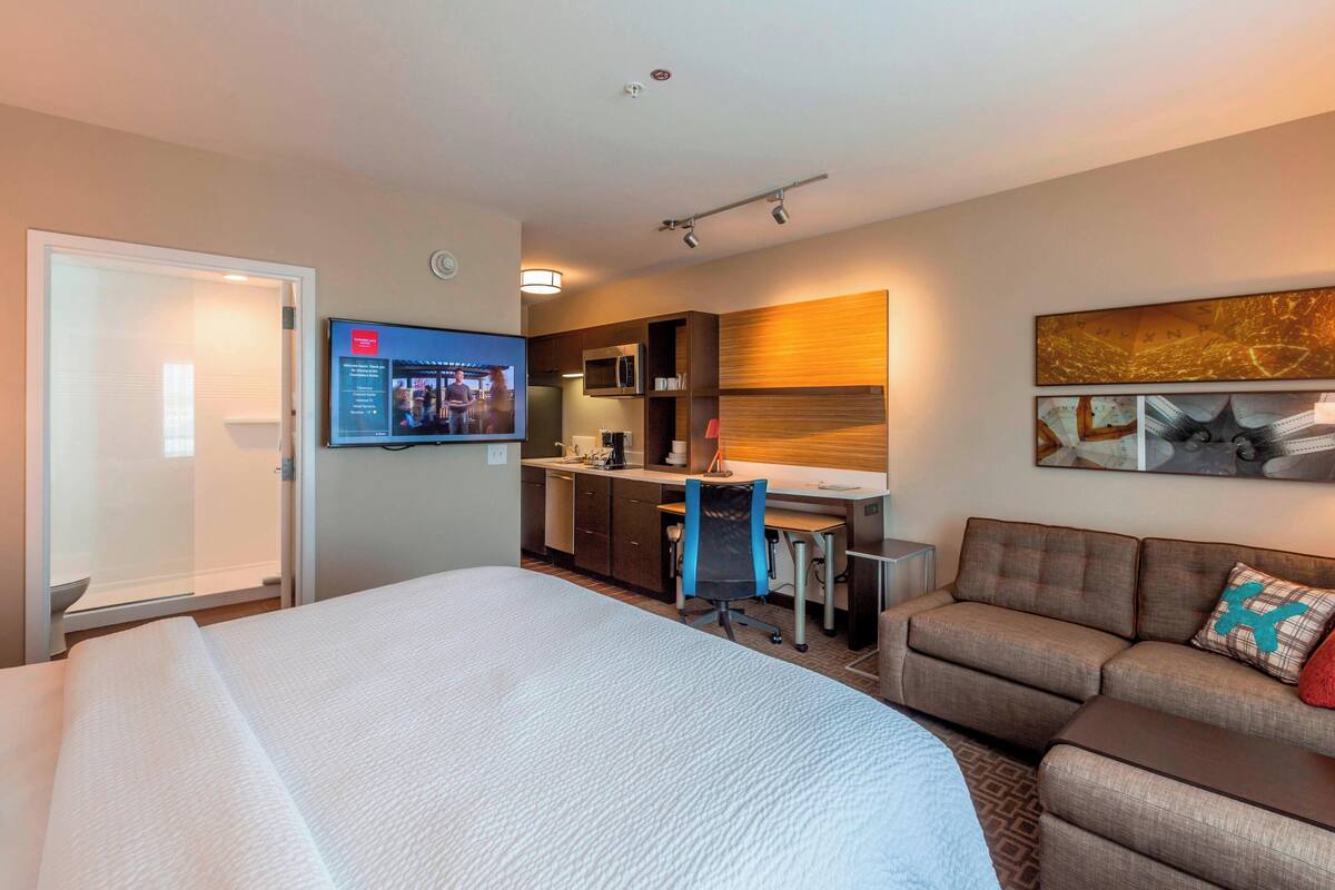Ein Hotelzimmer mit Bett, Schreibtisch, Sofa, Fernseher und Mikrowelle.