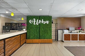 A reception area with a green wall, a wooden reception desk, and a 'Aloha' sign. - WorldMark Kihei (Kihei)