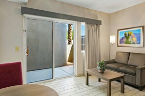 A modern living room with a sliding glass door leading to an outdoor area, a sofa, a coffee table, and a framed picture on the wall. - Worldmark Cathedral City (Cathedral City)
